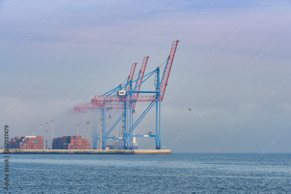 Cargo port cranes. Foggy and sea.