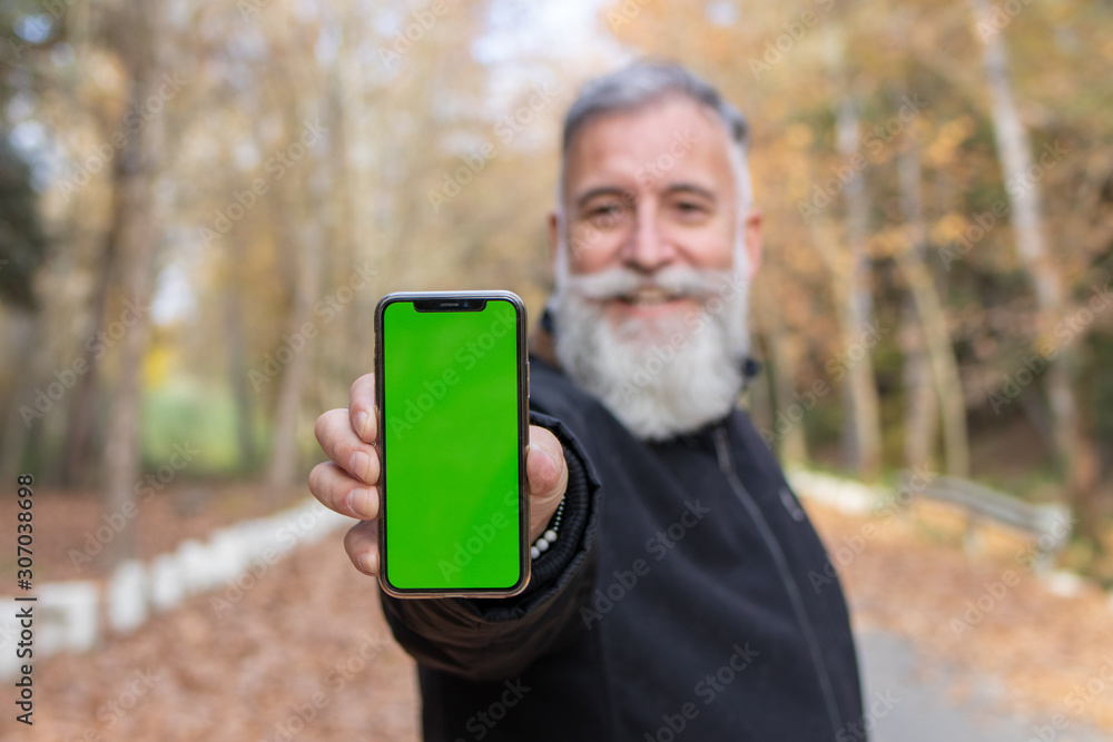 Elderly man with a beard teaching the smartphone with chromatic key background in the field Elderly man with a beard teaching the smartphone with chromatic key background in the field