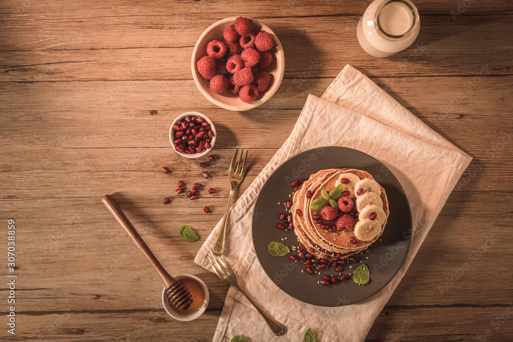 Pancakes with raspberries, banana slices, pomegranate seeds and honey Pancakes with raspberries, banana slices, pomegranate seeds and honey