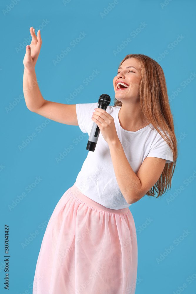 Beautiful young female singer with microphone on color background Beautiful young female singer with microphone on color background