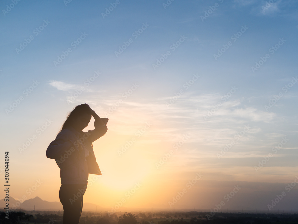sunrise or sunset stylish adult woman standing back looking toward the horizon with widely placed hands on background of bright sky,Romantic Girl,Blowing Long Hair.Successful.