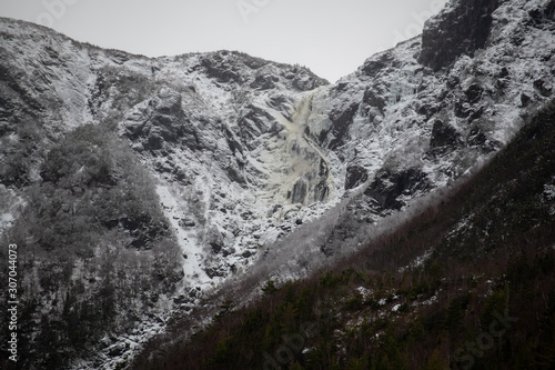 Large mountain with snow on the top and snow falling