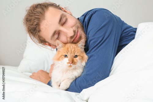 Morning of young man with cute cat in bedroom