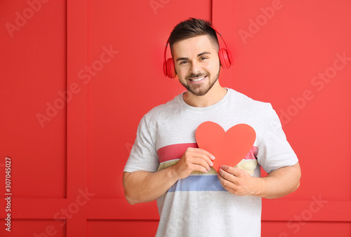 Handsome man with red heart on color background. Valentine's Day celebration © Pixel-Shot