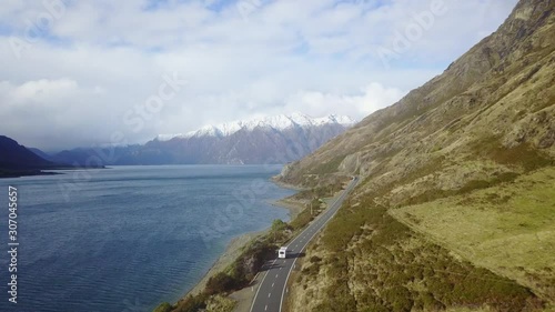 Wallpaper Mural Aerial Tracking shot of an rv driving on a coastal road next to the blue ocean with white snowy mountains in the background Torontodigital.ca