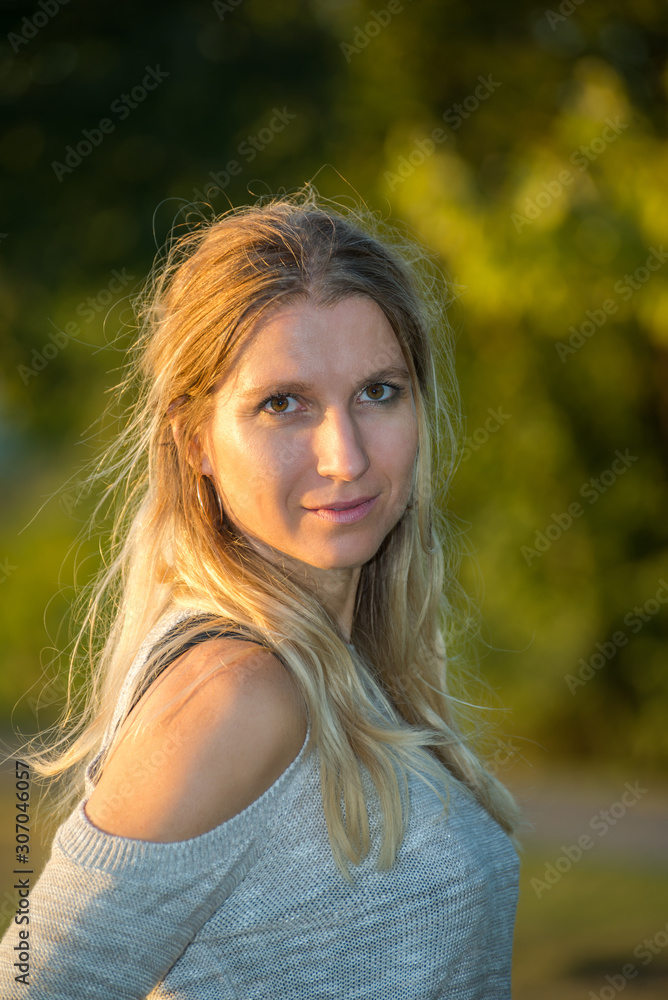 Attractive blonde young woman in a park with blurred background Attractive blonde young woman in a park with blurred background