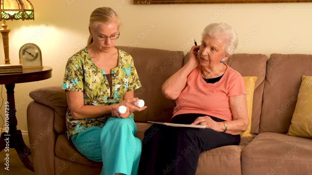 Home healthcare nurse going over medications with elderly woman while sitting in living room. Home healthcare nurse going over medications with elderly woman while sitting in living room.