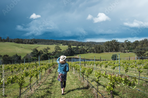 Young female walking in the vineyards in Tasmania, wearing hat and skirt, fashionable