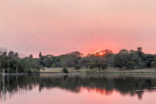 Bush fire smoke sunrise and park pond