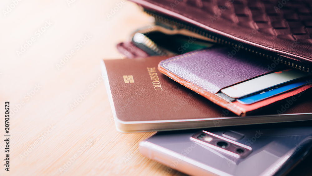 Closeup of traveler's stuffs in female purse who just arrived in Japan, wads of 10000 yen banknotes, foreigner passport, smartphone, credit and debit cards. Female solo travel, Business trip, Tourist. Closeup of traveler's stuffs in female purse who just arrived in Japan, wads of 10000 yen banknotes, foreigner passport, smartphone, credit and debit cards. Female solo travel, Business trip, Tourist.