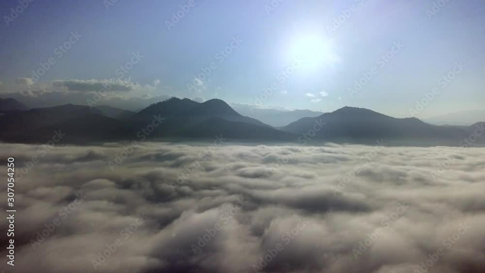 Slow aerial flight above the clouds towards mountains in the morning. Slow aerial flight above the clouds towards mountains in the morning.