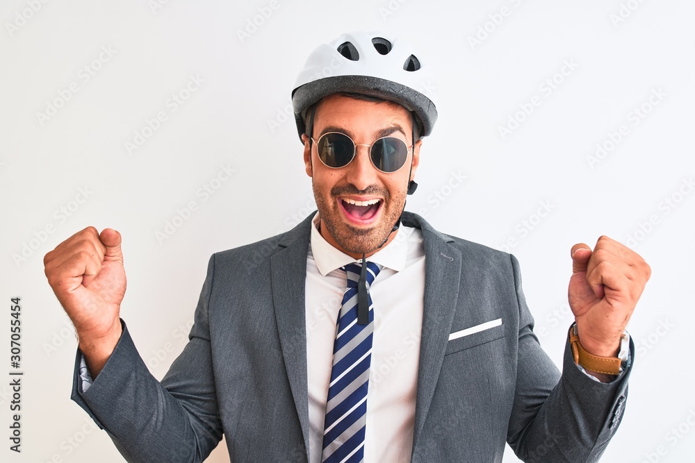 Young handsome business man wearing bike helmet and sunglasses over isolated background screaming proud and celebrating victory and success very excited, cheering emotion Young handsome business man wearing bike helmet and sunglasses over isolated background screaming proud and celebrating victory and success very excited, cheering emotion