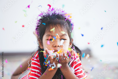 Cute asian child girl with colorful confetti to celebrate in her party
