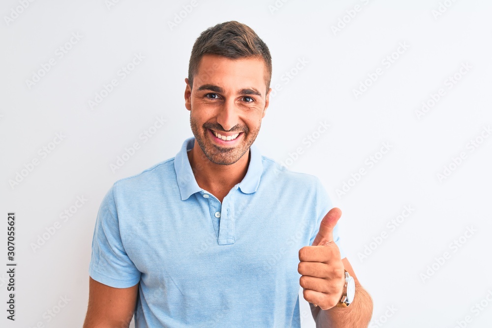 Young handsome elegant man wearing blue t-shirt over isolated background doing happy thumbs up gesture with hand. Approving expression looking at the camera with showing success. Young handsome elegant man wearing blue t-shirt over isolated background doing happy thumbs up gesture with hand. Approving expression looking at the camera with showing success.