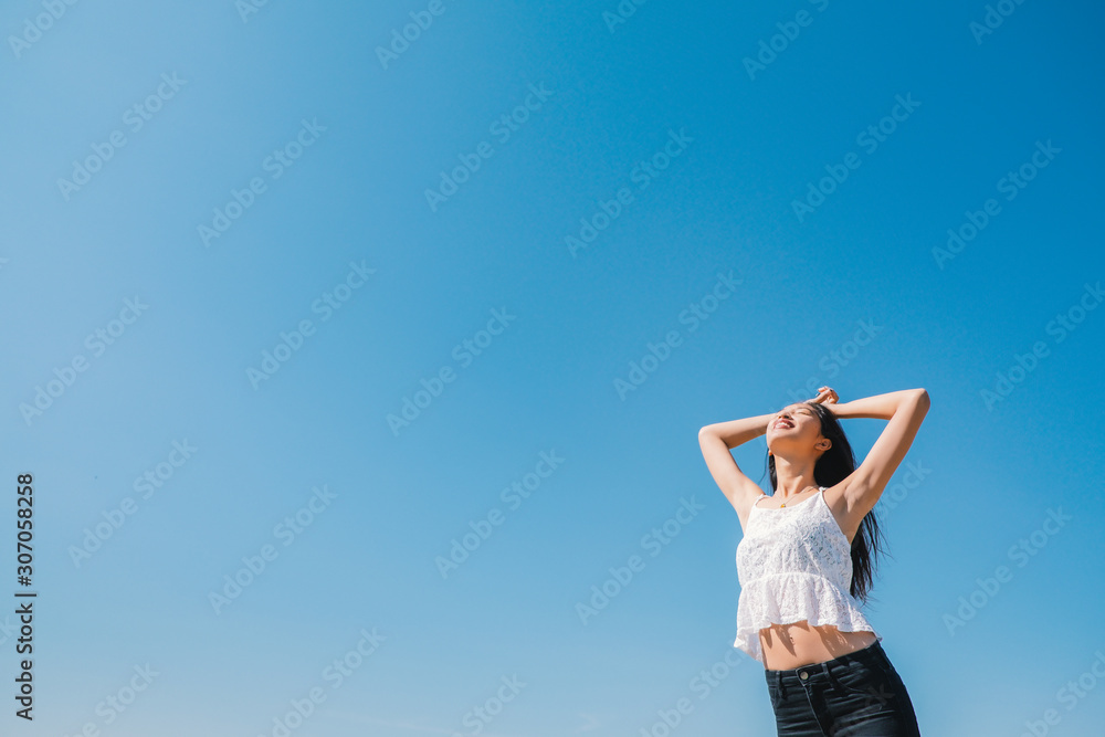Happy woman with tanned slim body breathing fresh air raising her arms up, enjoying a sunny summer holiday on beach destination against blue sky, outdoors. Travel and well being lifestyle. Happy woman with tanned slim body breathing fresh air raising her arms up, enjoying a sunny summer holiday on beach destination against blue sky, outdoors. Travel and well being lifestyle.