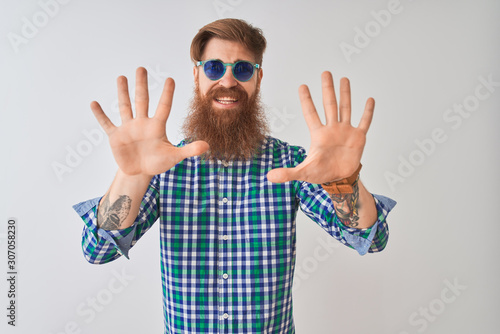 Young redhead irish man wearing casual shirt and sunglasses over isolated white background showing and pointing up with fingers number ten while smiling confident and happy.
