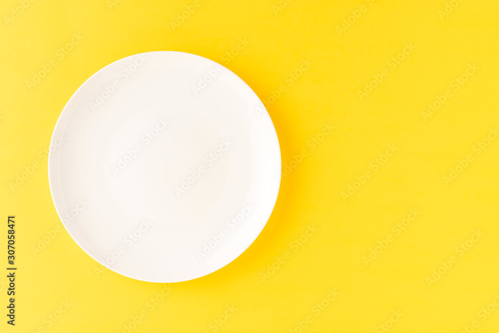 Overhead shot of blank white plate on yellow background. Flat lay Overhead shot of blank white plate on yellow background. Flat lay
