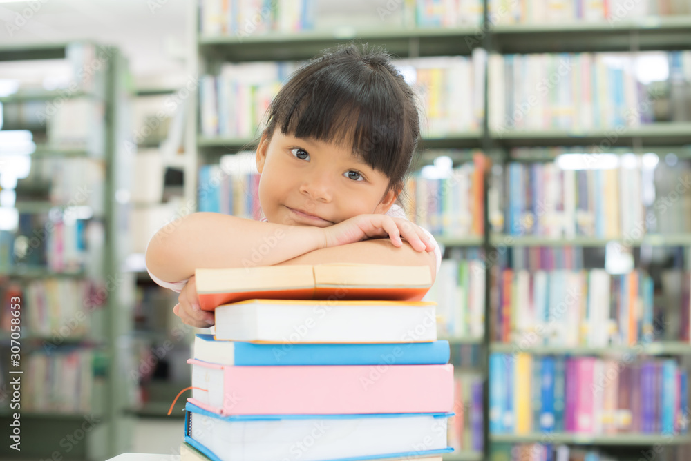 child girl holding a stack of books in the library child girl holding a stack of books in the library
