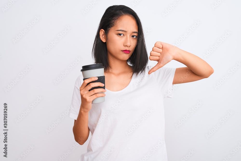 Young chinese woman drinking take away glass of coffee over isolated white background with angry face, negative sign showing dislike with thumbs down, rejection concept Young chinese woman drinking take away glass of coffee over isolated white background with angry face, negative sign showing dislike with thumbs down, rejection concept