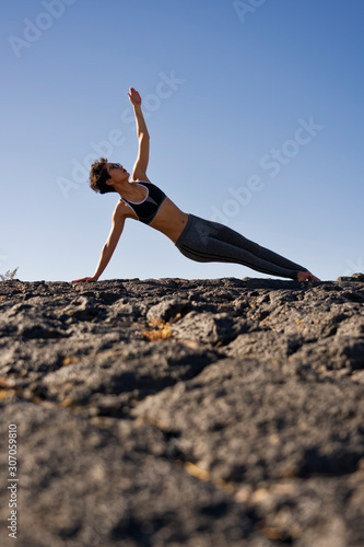 A woman does yoga at a lava field 