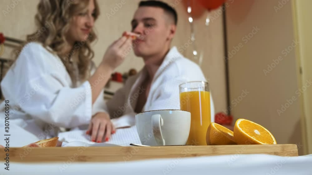 Young couple lovers romantic breakfast in bed. Lovely girlfriend feeds her boyfriend a delicious sandwich Young couple lovers romantic breakfast in bed. Lovely girlfriend feeds her boyfriend a delicious sandwich