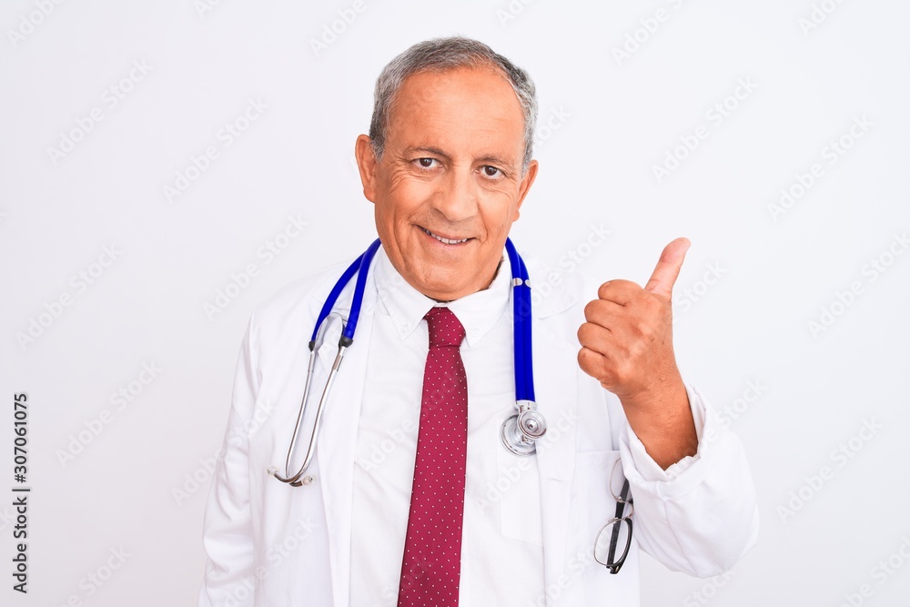 Senior grey-haired doctor man wearing stethoscope standing over isolated white background doing happy thumbs up gesture with hand. Approving expression looking at the camera showing success. Senior grey-haired doctor man wearing stethoscope standing over isolated white background doing happy thumbs up gesture with hand. Approving expression looking at the camera showing success.