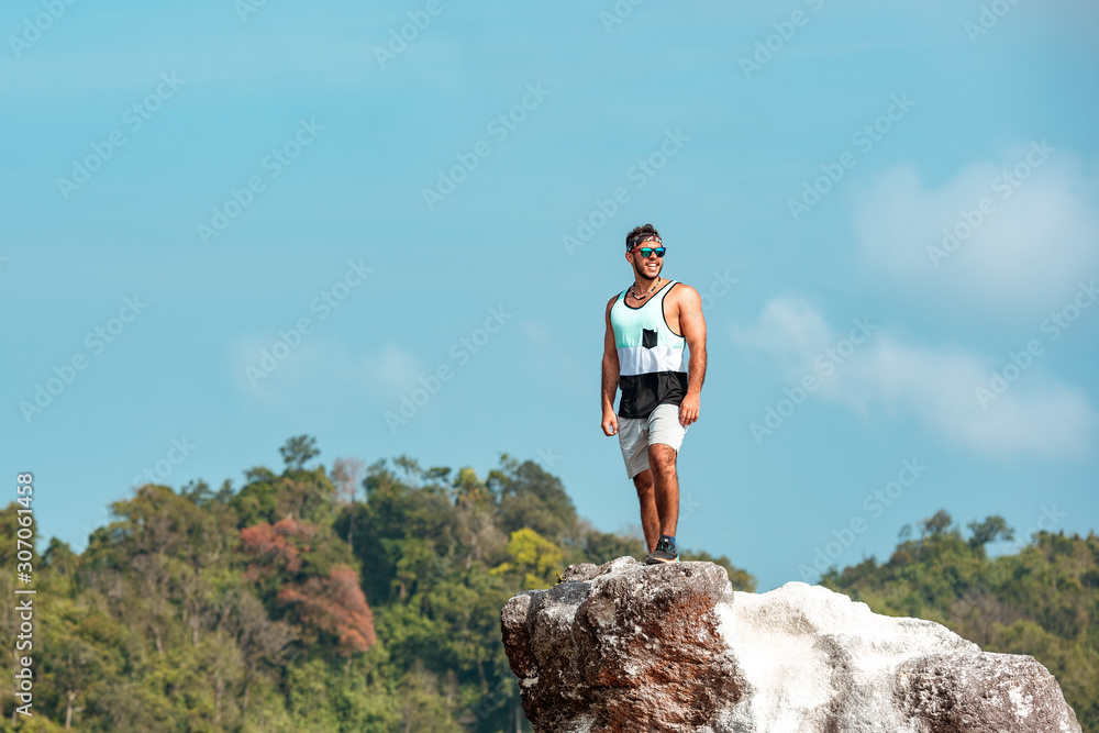Sporty strong man on big rock mountain top