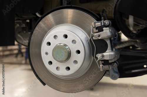 The brake mechanism of a modern car. Rear brake disc of a car with caliper, pads closeup. Technical photography.