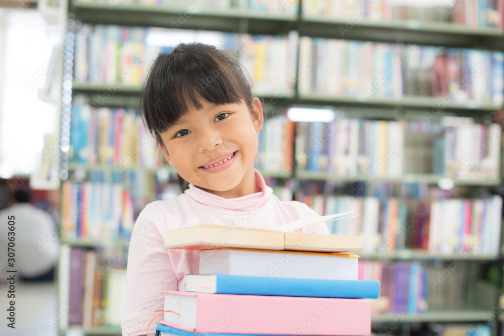 child girl holding a stack of books in the library child girl holding a stack of books in the library