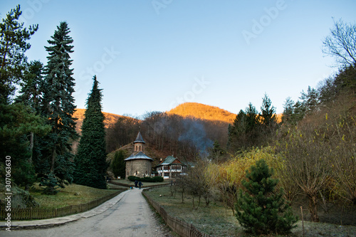 Beautiful church of Saint Arsenie Boca seen from a distance, between trees on a sunny autumn day at Prislop Monastery, Romania photo