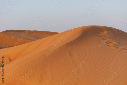 Desert at sunrise brings out bold burnt orange colored sand making a great desert landscape on rippling or rolling hills in Ras al Khaimah  in the United Arab Emirates.