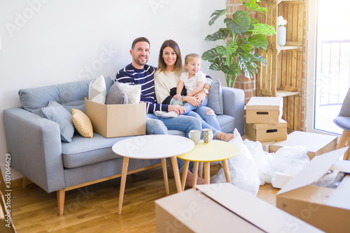 Beautiful family with kid sitting on the sofa drinking coffee at new home around cardboard boxes © Krakenimages.com