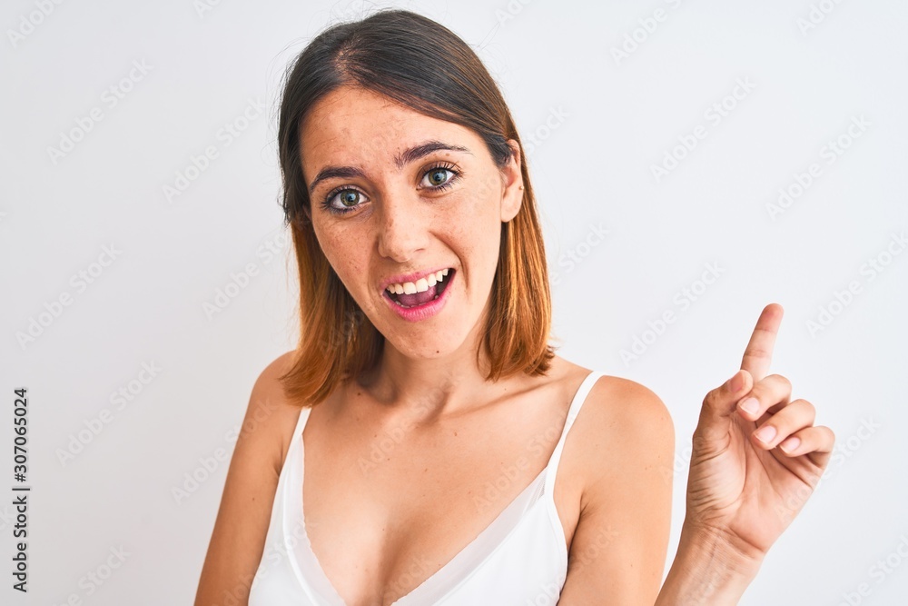 Beautiful redhead woman wearing casual white t-shirt over isolated background very happy pointing with hand and finger to the side Beautiful redhead woman wearing casual white t-shirt over isolated background very happy pointing with hand and finger to the side