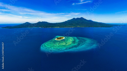 Beautiful Mantigue island with the volcanic Camiguin Island resting behind it while it dwells in the vibrant blue waters of the Philippines. photo