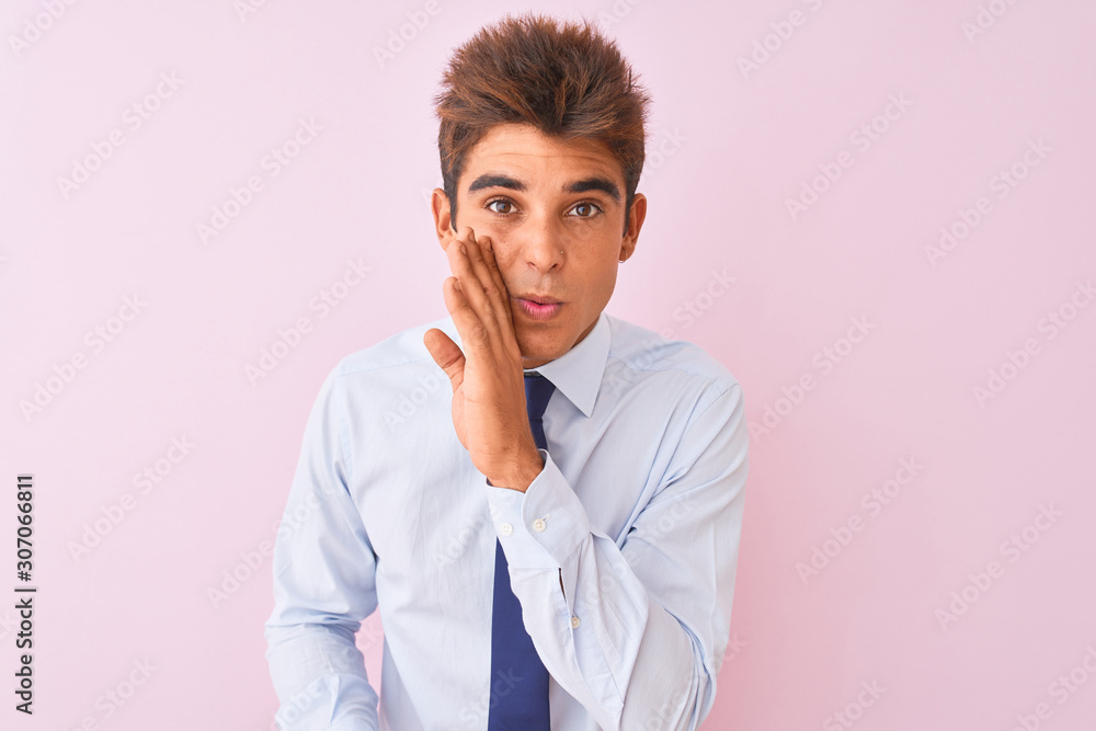 Young handsome businessman wearing shirt and tie standing over isolated pink background hand on mouth telling secret rumor, whispering malicious talk conversation Young handsome businessman wearing shirt and tie standing over isolated pink background hand on mouth telling secret rumor, whispering malicious talk conversation