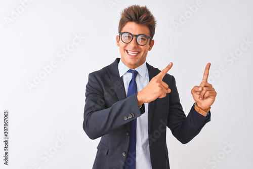 Young handsome businessman wearing suit and glasses over isolated white background smiling and looking at the camera pointing with two hands and fingers to the side.