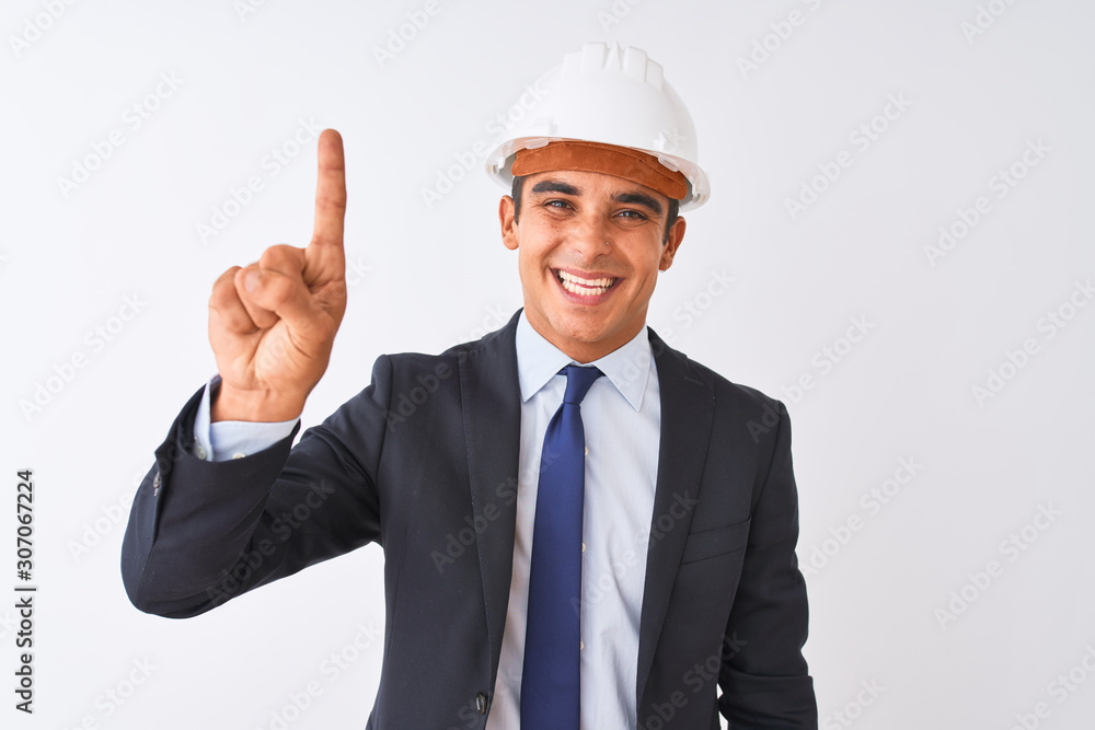 Young handsome architect man wearing suit and helmet over isolated white background showing and pointing up with finger number one while smiling confident and happy.