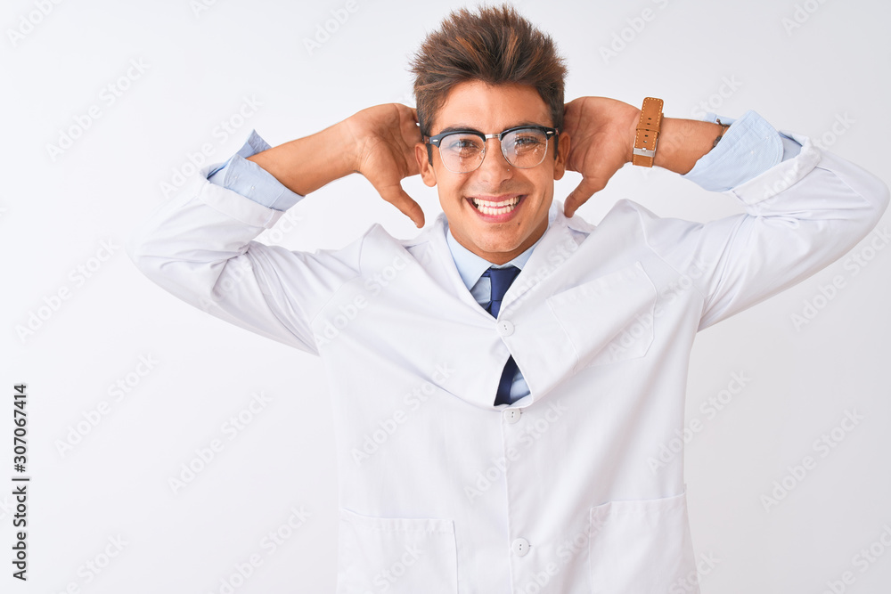 Young handsome sciencist man wearing glasses and coat over isolated white background relaxing and stretching, arms and hands behind head and neck smiling happy Young handsome sciencist man wearing glasses and coat over isolated white background relaxing and stretching, arms and hands behind head and neck smiling happy