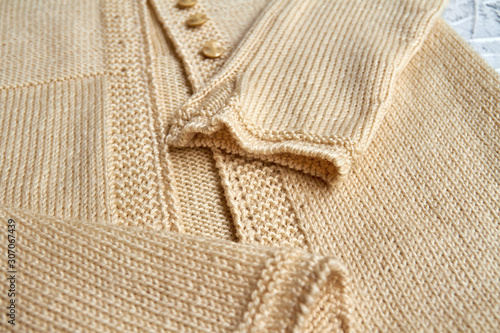 Sleeves on a beige knitted sweater. Closeup, selective focus