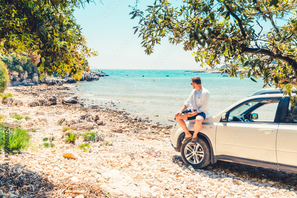 man with coffee cup standing near car at sea summer beach