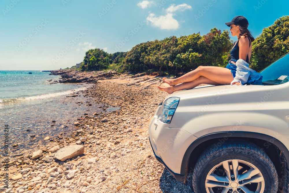 woman laying at car hood with view of sea summer beach