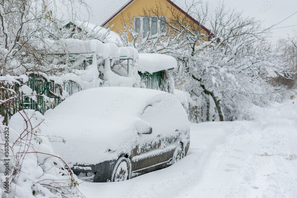 Snow-covered machine. Car under the snow. Lots of snow and big snowdrifts on the street. Vehicles are completely covered in snow. Cold winter weather