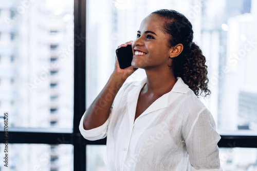 Smiling beautiful professional business african american black woman working and using smartphone standing in office
