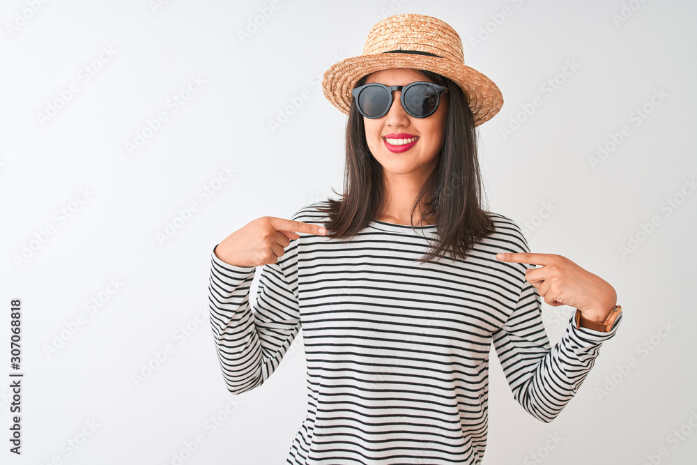 Chinese woman wearing striped t-shirt hat sunglasses standing over isolated white background looking confident with smile on face, pointing oneself with fingers proud and happy. Chinese woman wearing striped t-shirt hat sunglasses standing over isolated white background looking confident with smile on face, pointing oneself with fingers proud and happy.