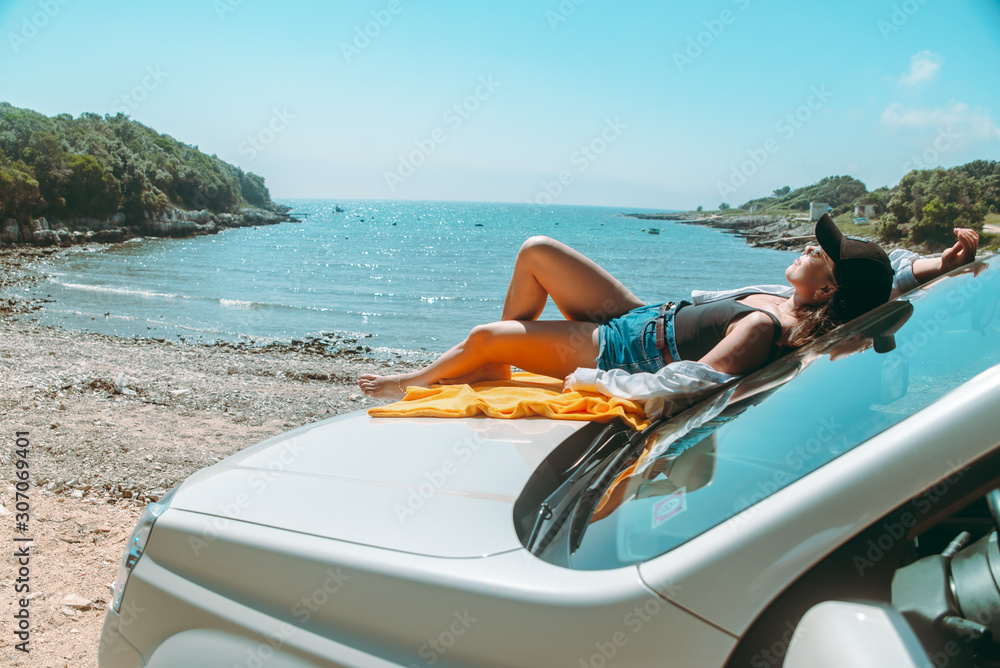 happy woman at sea summer beach sitting at car hood