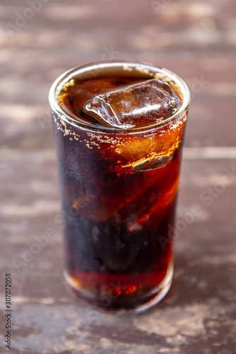 Pop or cola water in glass on the wooden table.