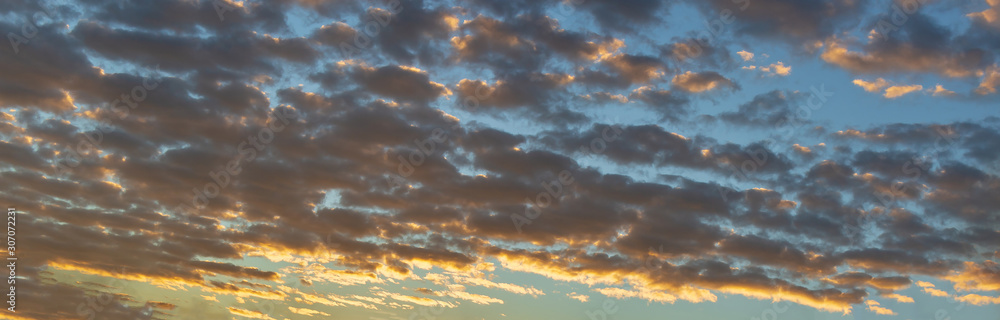 Panorama or panoramic dramatic blue sky and warm light clouds at sunrise or sunset on morning or evening time for background or backdrop.