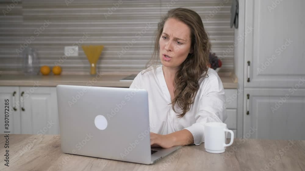 Sad woman working laptop computer at kitchen Sad woman working laptop computer at kitchen
