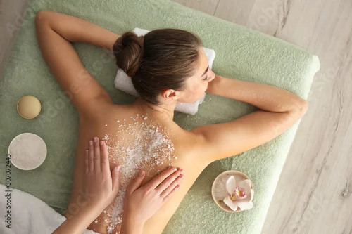 Obraz Młoda kobieta ma ciało szorowania procedurę z morze solą w zdroju salonie, odgórny widok