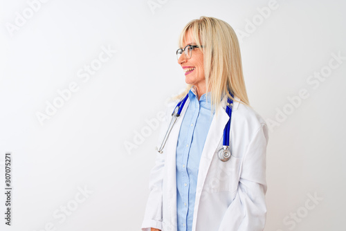 Middle age doctor woman wearing glasses and stethoscope over isolated white background looking away to side with smile on face, natural expression. Laughing confident.